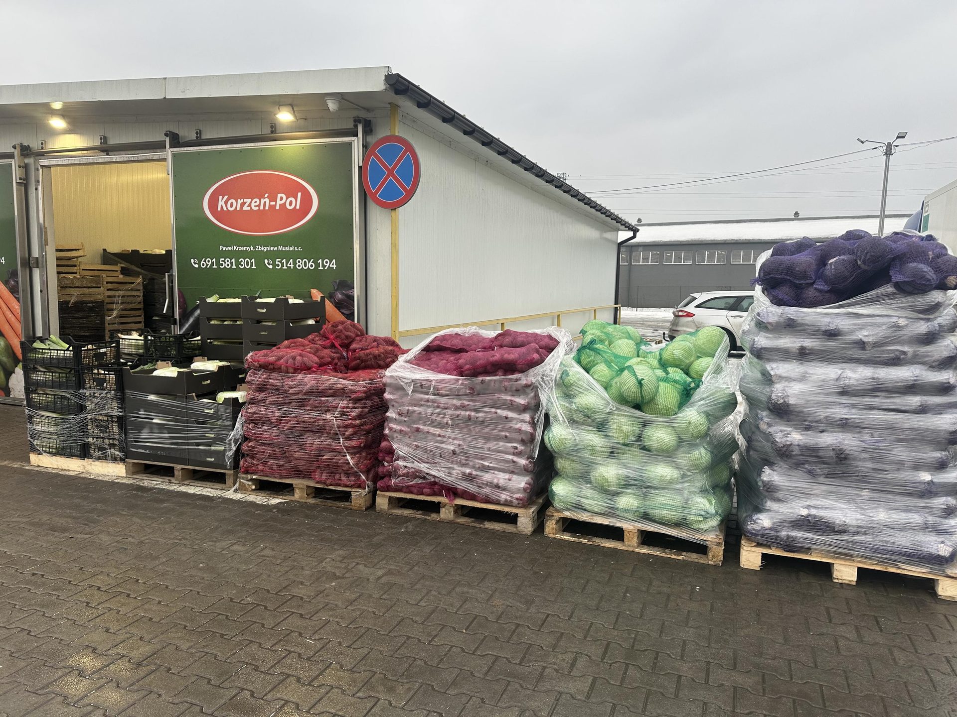 Witryna firmowa Korzeń-Pol z paletami warzyw na placu targowym Rybitwy w Krakowie